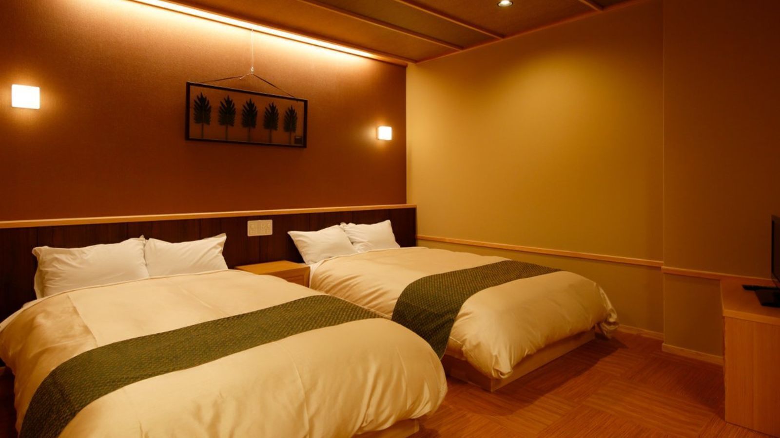A hotel room with two beds, a television, and a wall-mounted picture of trees.