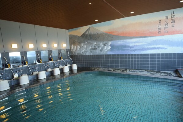 Una piscina con paredes de azulejos y un mural de un paisaje montañoso.