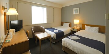 Habitación de hotel con dos camas, un escritorio, una silla, un televisor y una ventana.
