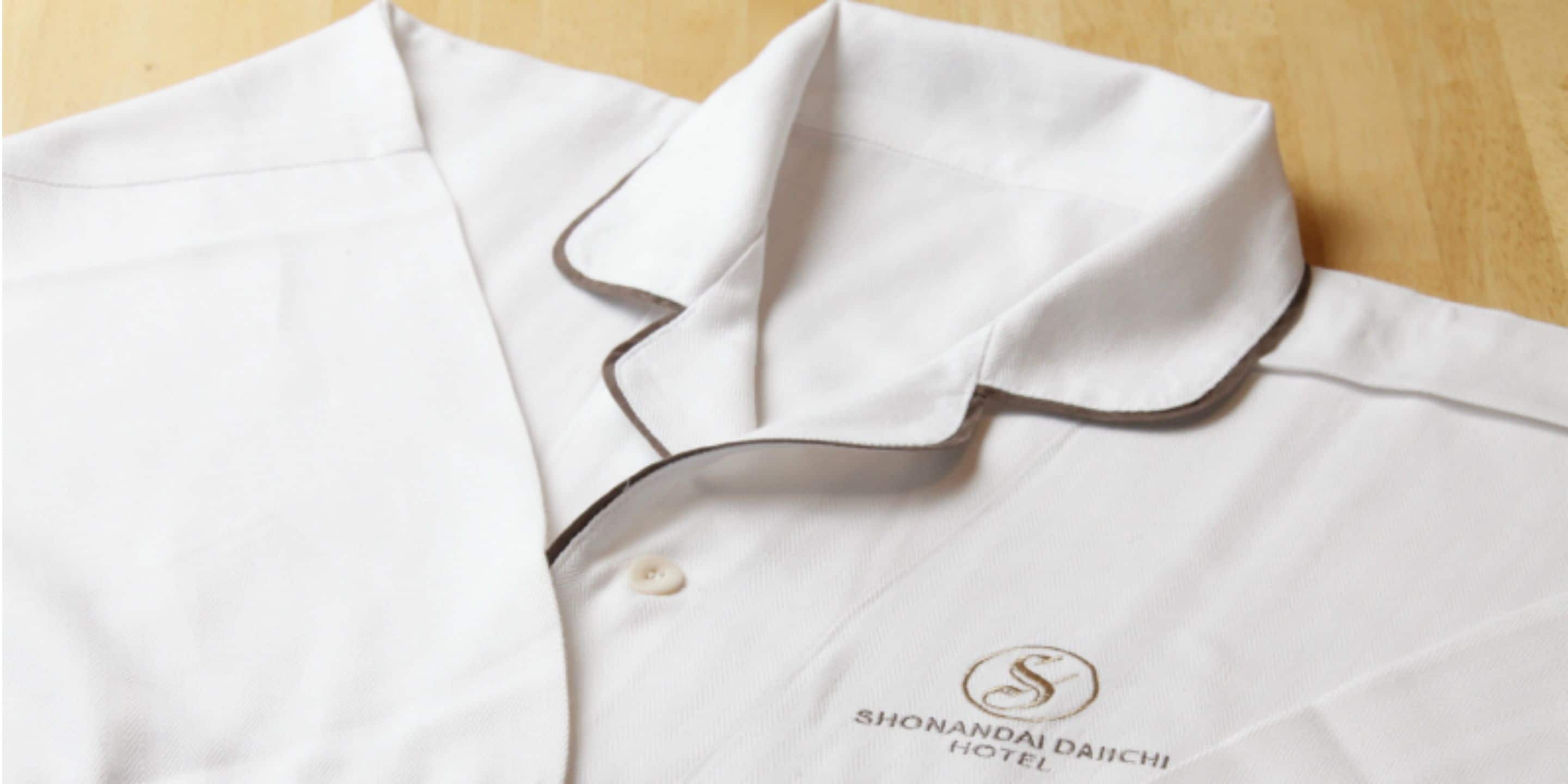 A neatly folded white shirt with a collar and a button.