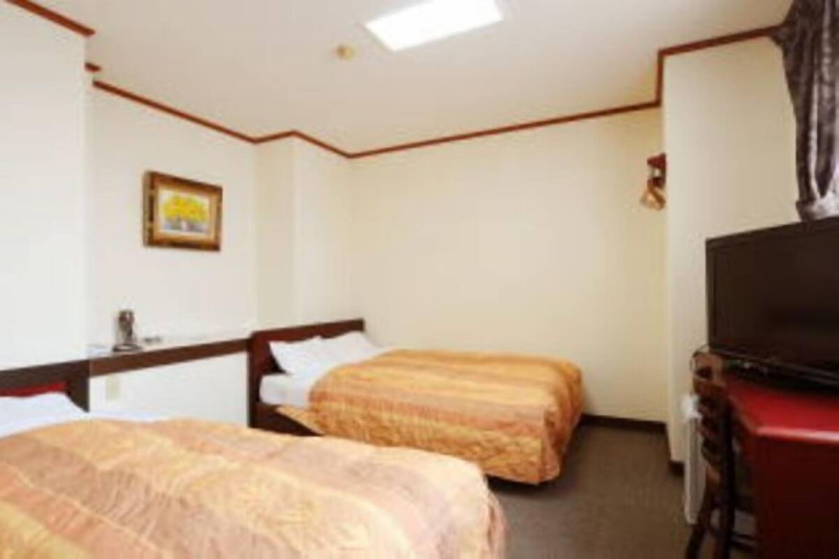 A hotel room with two beds, a television, and a small table.