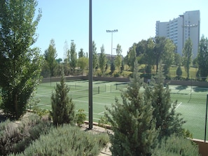A tennis court surrounded by trees and a building in the background.