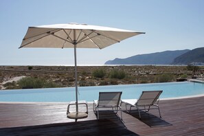 A poolside area with two lounge chairs and a large umbrella.