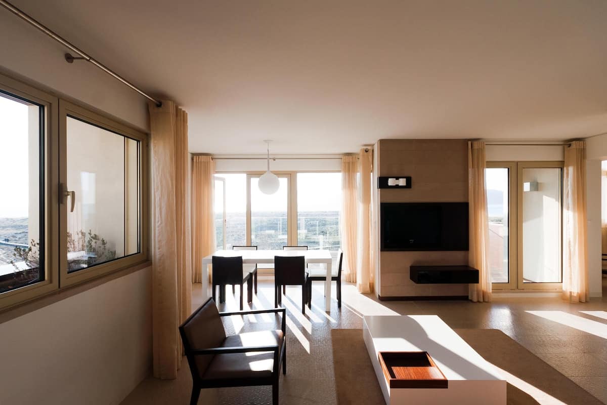 Una sala de estar moderna con comedor, ventanas grandes y un televisor de pantalla plana.