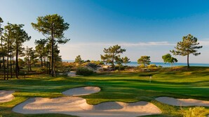 Un campo da golf con bunker di sabbia, alberi e cielo sereno.