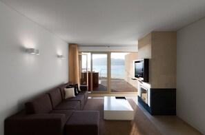 A modern living room with a sofa, a coffee table, and a flat-screen TV mounted on a wall.