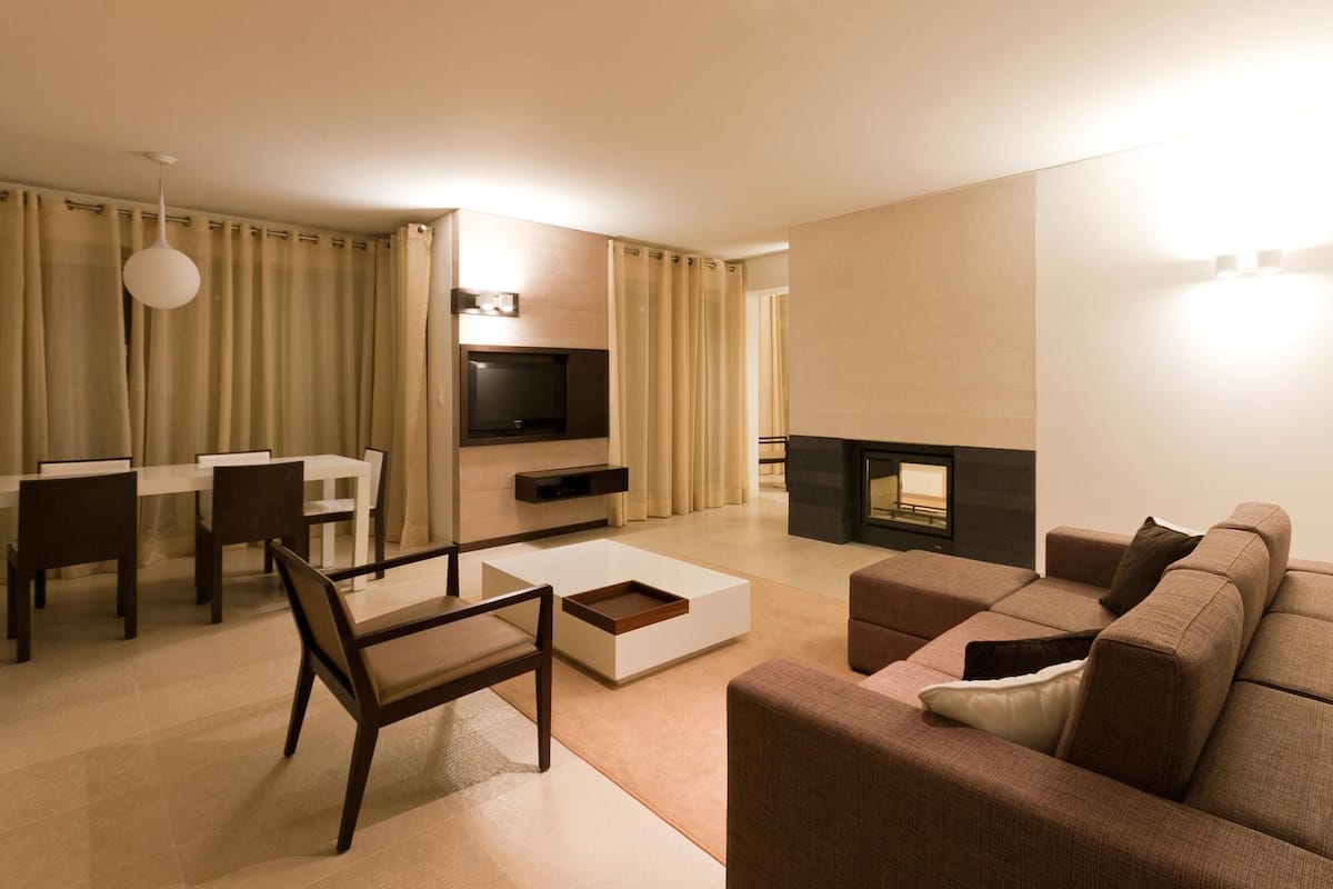 Una sala de estar moderna con sofá, mesa de centro, televisor, chimenea y comedor.