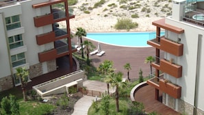 A modern hotel with a pool, outdoor seating, and a view of the desert landscape.