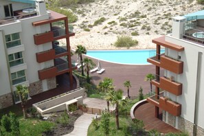 A modern hotel with a pool, outdoor seating, and a view of the desert landscape.