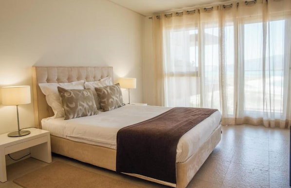 A neatly made bed with a brown blanket, two bedside lamps, and a nightstand.