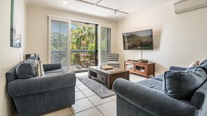 Ein Wohnzimmer mit grauen Sofas, einem Couchtisch und einem Fernseher an der Wand.