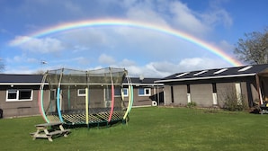A house with a large garden, a swing set, and a rainbow in the sky. - Lakefront Resort (Rotorua)
