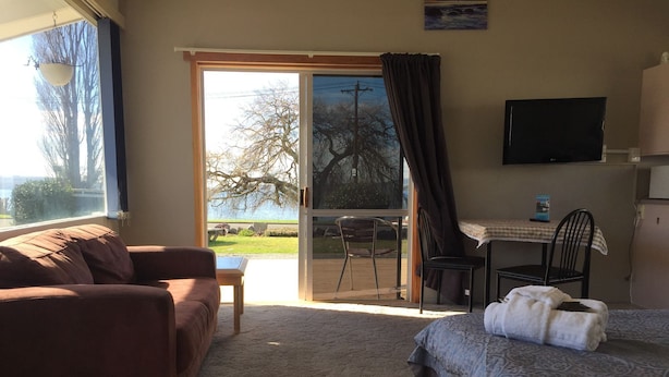 A bedroom with a bed, a sofa, a desk, and a chair. - Lakefront Resort (Rotorua)