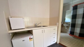 Una cocina compacta con refrigerador, pileta y una pequeña mesada.