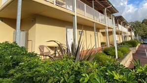 Una hilera de edificios de dos pisos con balcones, rodeados de vegetación.