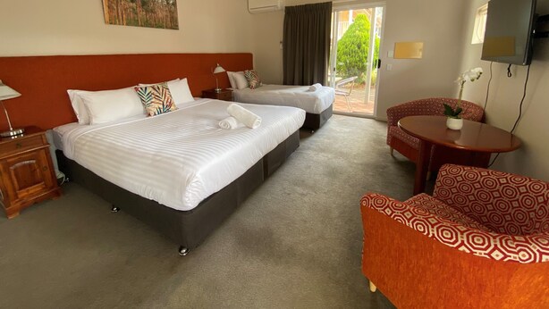 Habitación de hotel con dos camas, un sofá, un televisor y vistas al exterior.