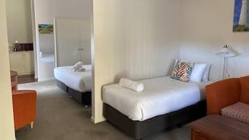 A hotel room with two beds, a sofa, a small table, and a painting on the wall.