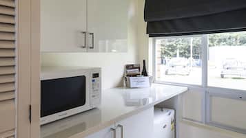 Une petite cuisine équipée d’un four à micro-ondes, de placards et d’une fenêtre donnant sur l’extérieur.