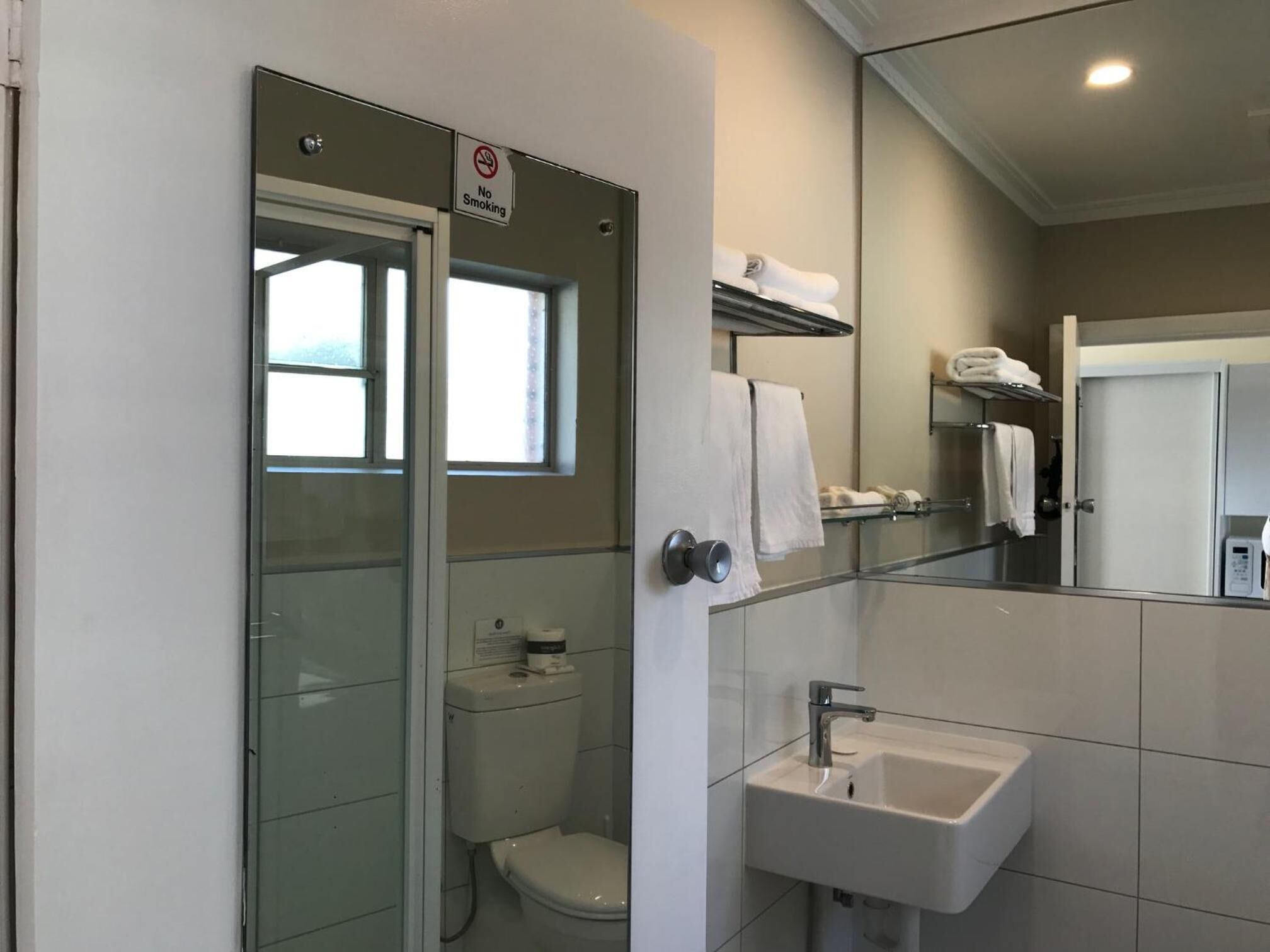 Une salle de bain moderne avec une douche à parois de verre, des toilettes, un lavabo et un miroir.