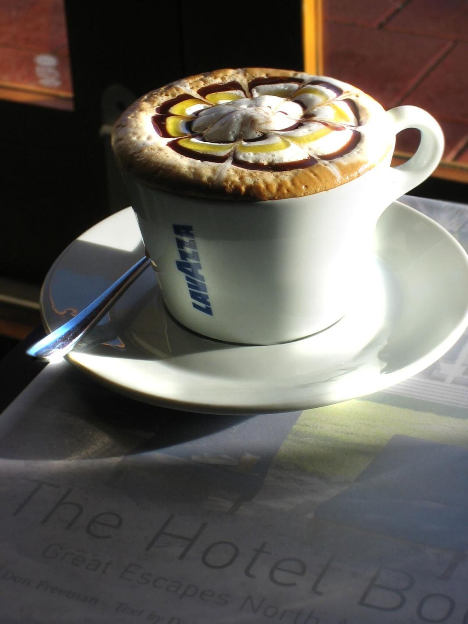 A cup of coffee with a decorative design on the foam, placed on a saucer.