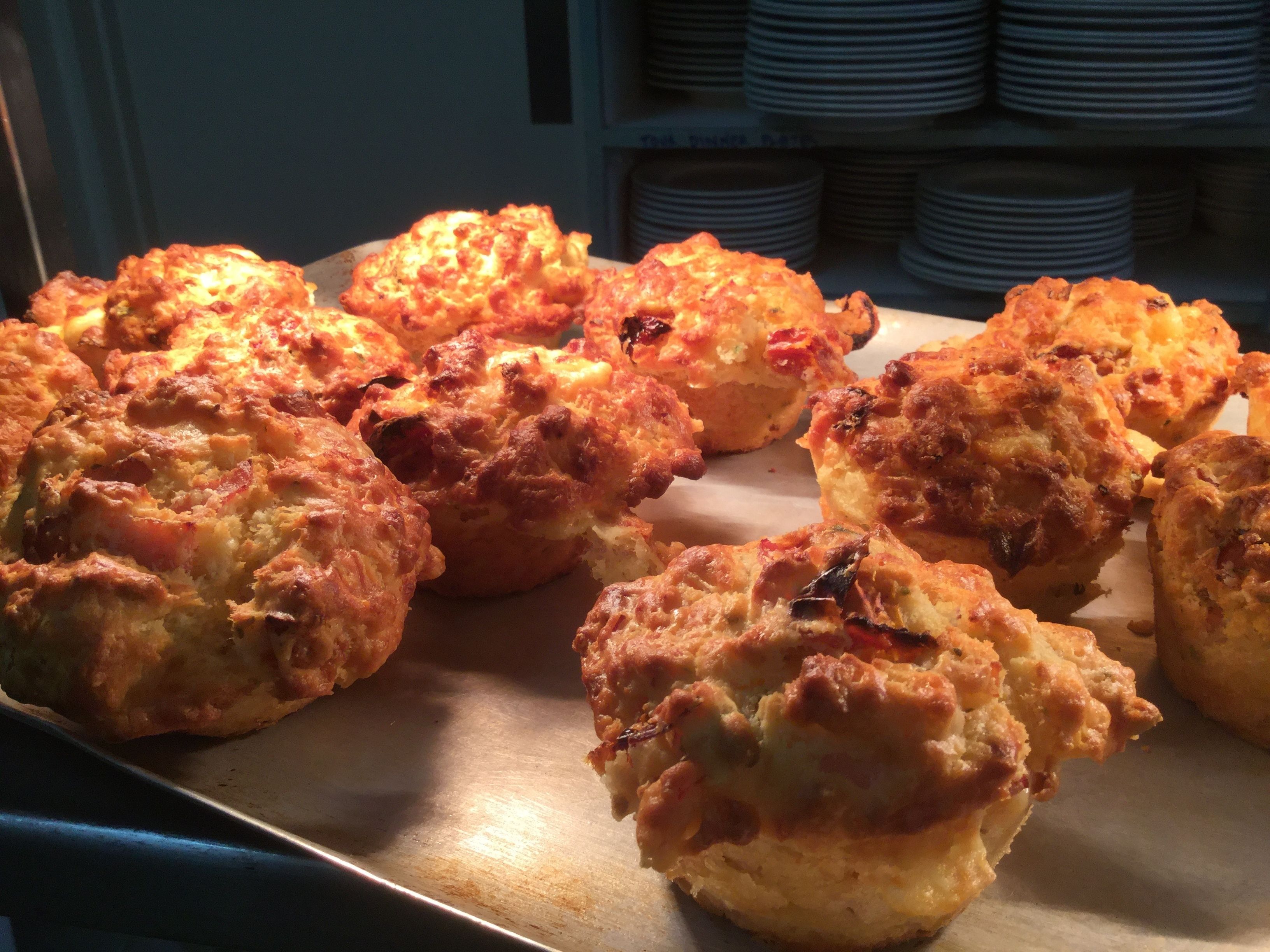 A tray of freshly baked biscuits with melted cheese on a metal surface.