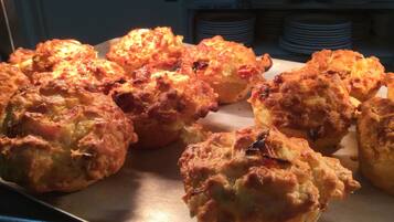 A tray of freshly baked biscuits with melted cheese on a metal surface.