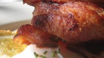 Une assiette de petit-déjeuner avec du bacon, un œuf poché et des toasts.