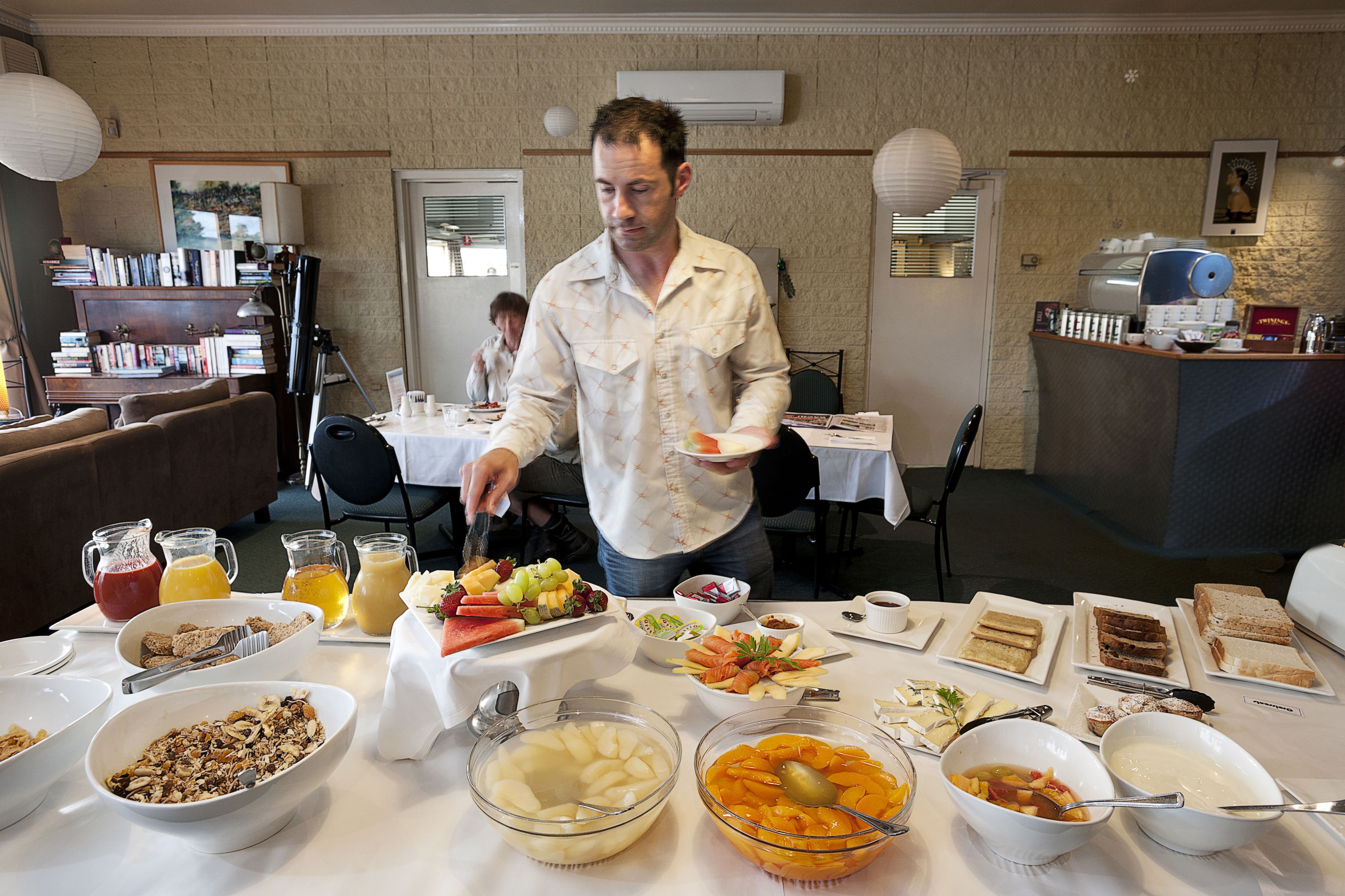 A breakfast buffet with various food items and a man serving himself.