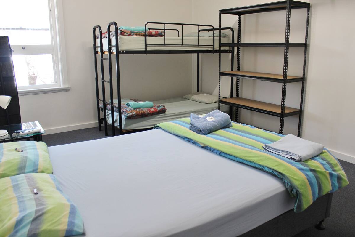 A bunk bed room with a desk and a window.