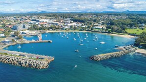 An aerial view of a coastal town with a marina, rocky breakwater, and residential areas.