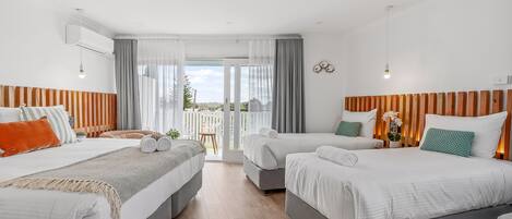 Quarto de hotel com duas camas, varanda e vista para o verde.