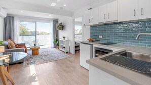 A modern kitchen with white cabinets, a blue-tiled backsplash, and a stainless steel sink.