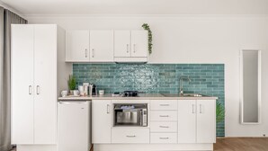 A modern kitchen with white cabinets, a built-in oven, and a teal backsplash.