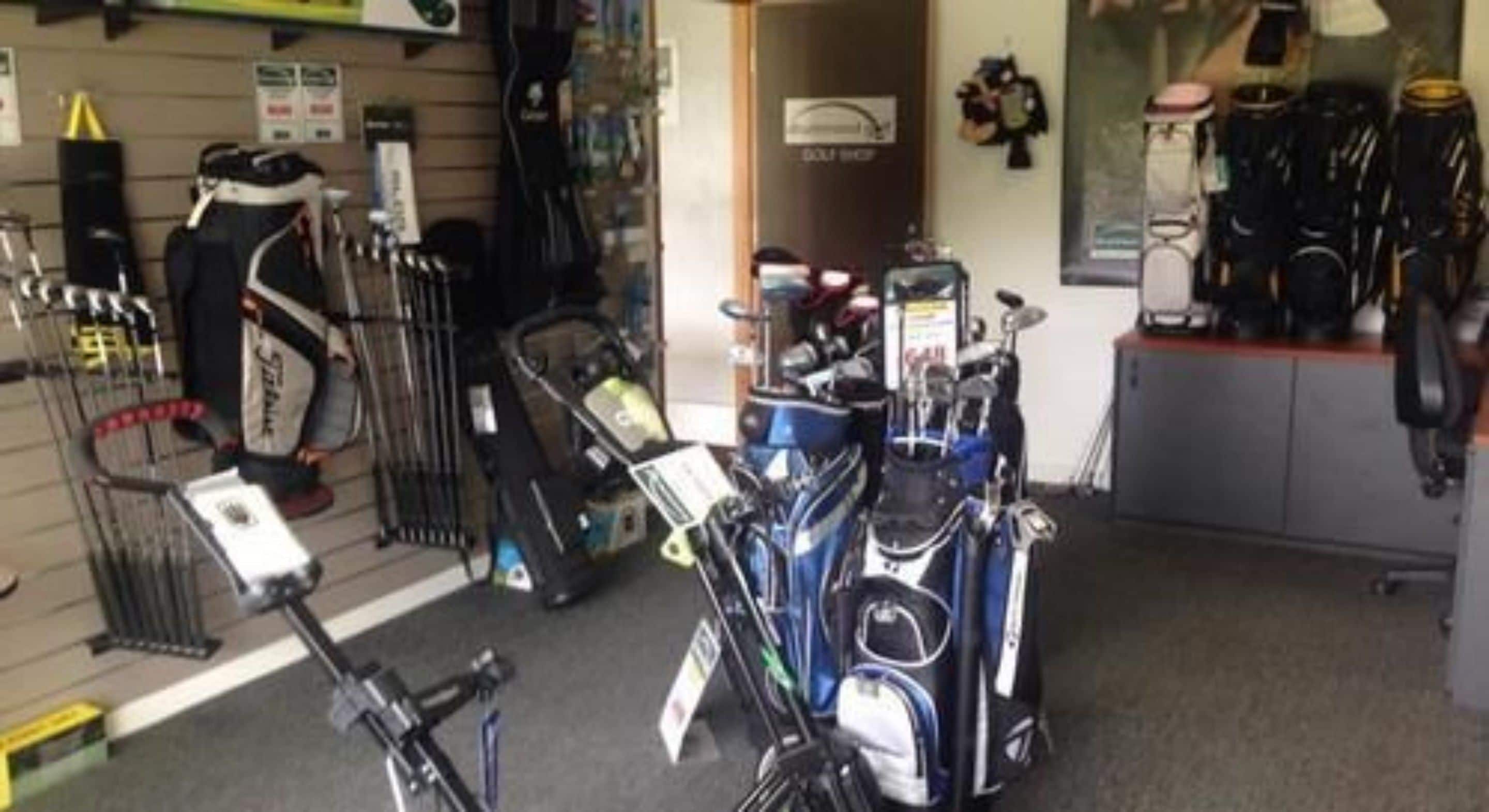 A golf equipment store with various golf clubs and bags displayed on shelves and racks.