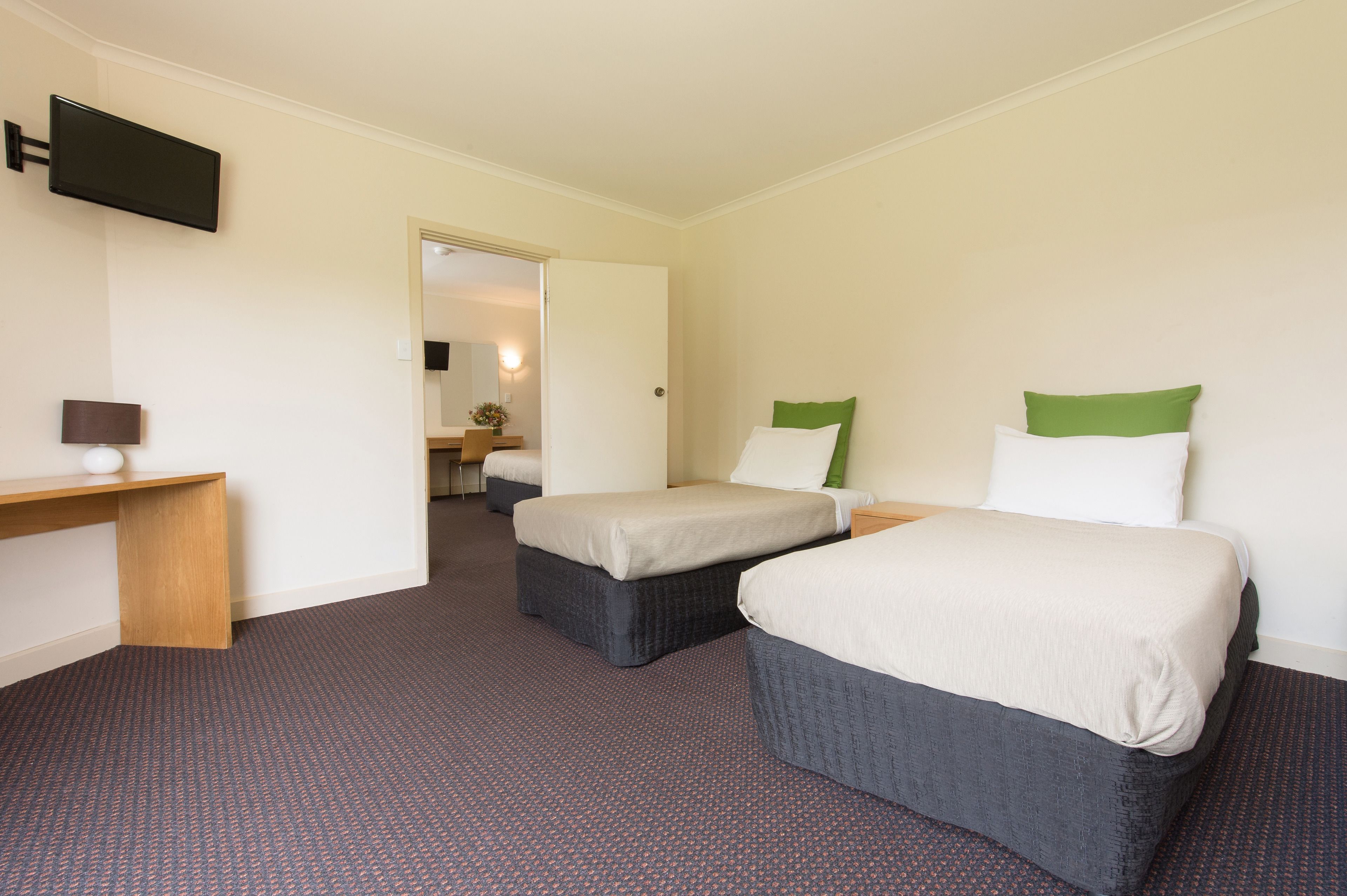 A hotel room with two beds, a desk, and a television.