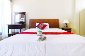 A neatly made bed with a red and white bedspread, a rolled towel, and a can of 'Vella' on the bed. - Jungut Guest House By Zuzu (Ubud)