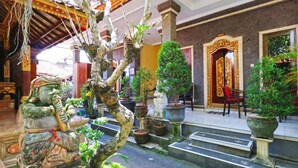 A traditional Balinese temple interior with stone statues, a staircase, and potted plants. - Jungut Guest House By Zuzu (Ubud)
