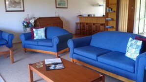 Ein Wohnzimmer mit zwei blauen Sofas, einem Holztisch und einer Holzkommode.