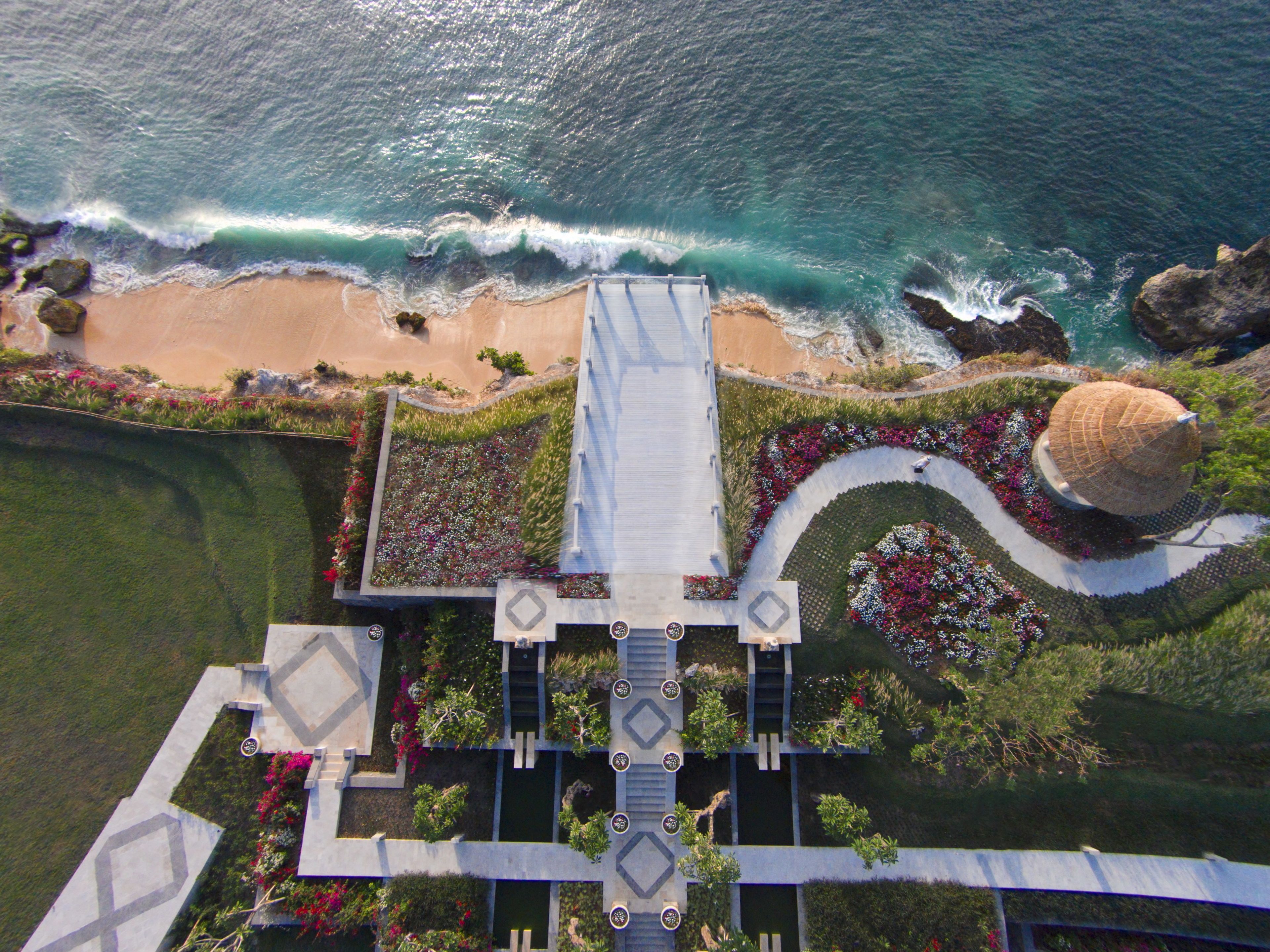 Vista aérea de un resort con playa, un camino central y una gran estructura en forma de cúpula.