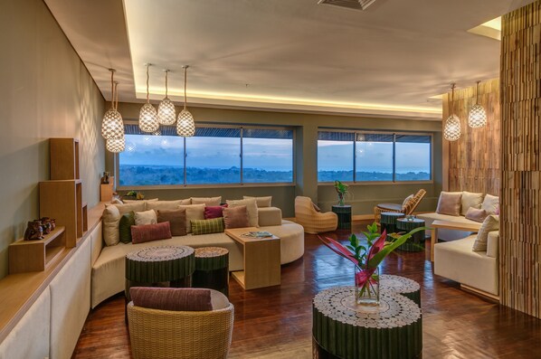 A spacious living area with a sofa set, a coffee table, and a view of the landscape through large windows. - AYANA Villas Bali (Jimbaran)
