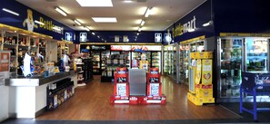 A store interior with shelves stocked with various products, a refrigerated section, and promotional displays. - Park Beach Hotel Motel (Coffs Harbour)