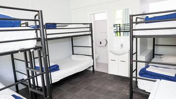 Un dormitorio con literas, un lavamanos y un espejo.