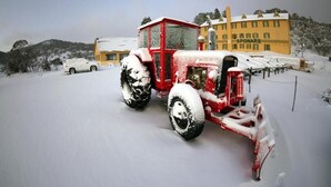 Un tracteur rouge recouvert de neige, garé devant un bâtiment portant l’inscription « SPONARS ».