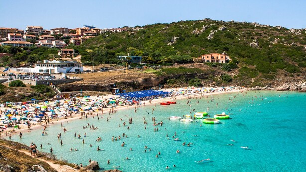 A beach with clear turquoise water, numerous umbrellas, and people swimming and sunbathing. - Residence La Reggia di Nausicaa (Santa Teresa di Gallura)