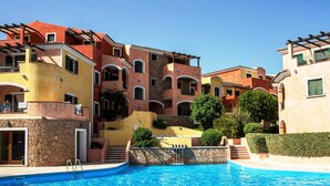 A resort with colorful buildings, a swimming pool, and stone walls. - Residence La Reggia di Nausicaa (Santa Teresa di Gallura)