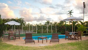 An outdoor pool area with lounge chairs, a table, and umbrellas. - Pousada Praia de Imbassaí (Mata de São João)