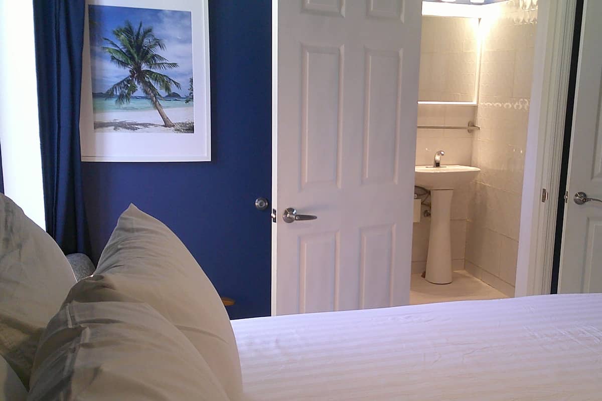 Een hotelkamer met een bed, een zichtbare badkamer door een open deur en een lijst aan de muur.