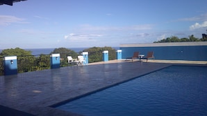 A rooftop pool with a view of the ocean, surrounded by blue walls and white chairs. - E&J Boutique Residences (Sosúa)