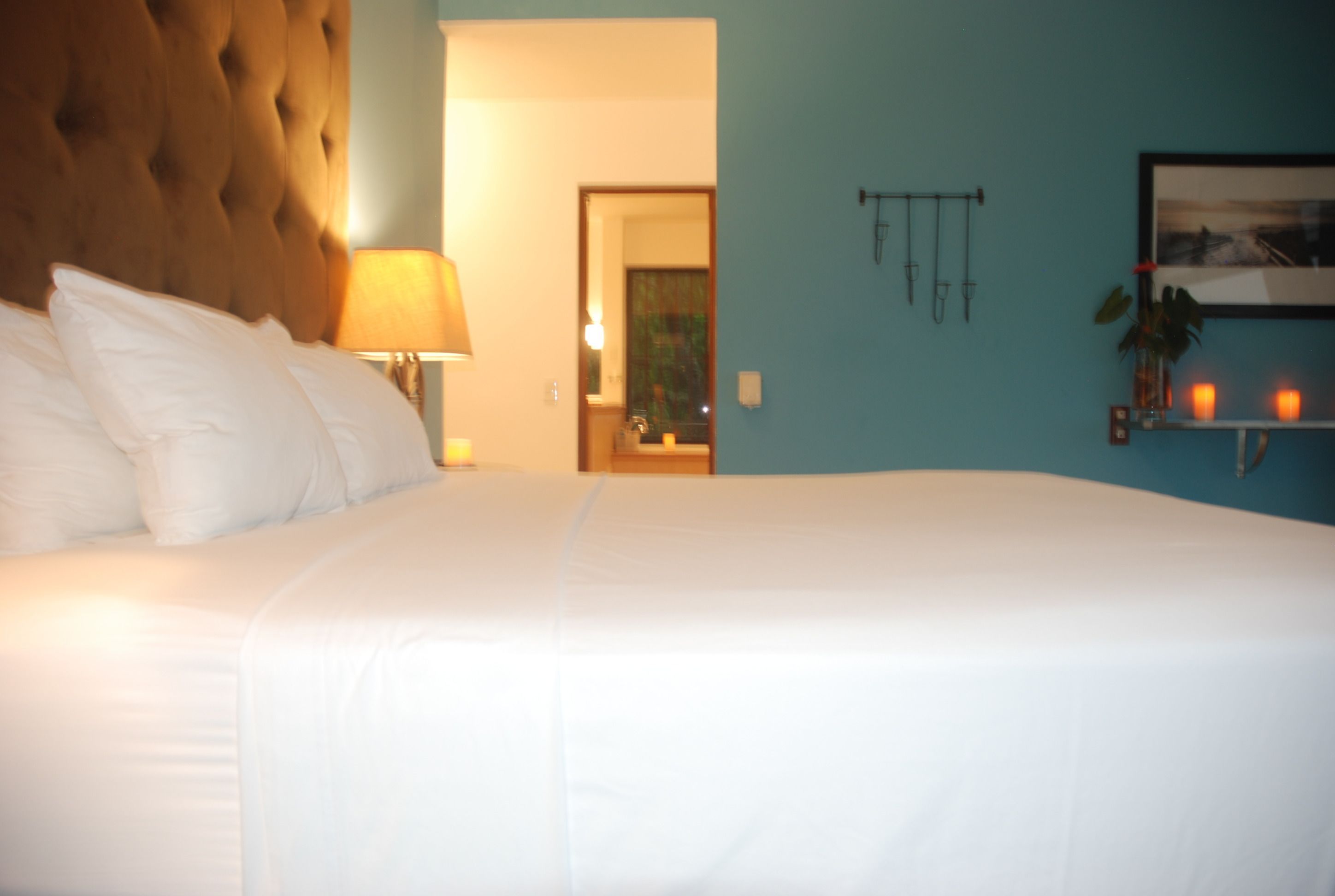 A large bed with white linens, a tufted headboard, and a bedside lamp.