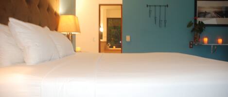A large bed with white linens, a tufted headboard, and a bedside lamp.